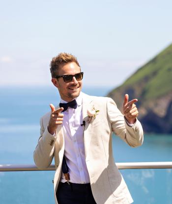 A groom posing for photographs on the platform overlooking the bay at Sandy Cove Hotel's The Venue