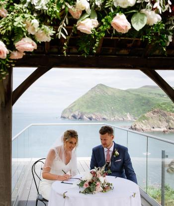 A bride and groom signing the marriage licence under the gazebo at The Venue, Sandy Cove Hotel