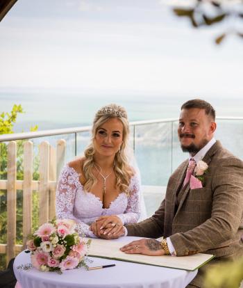 Bride and groom sat down outside with beautiful view behind them