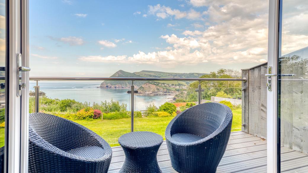 Two chairs and a table on the balcony overlooking the bay in Room 43 at Sandy Cove Hotel