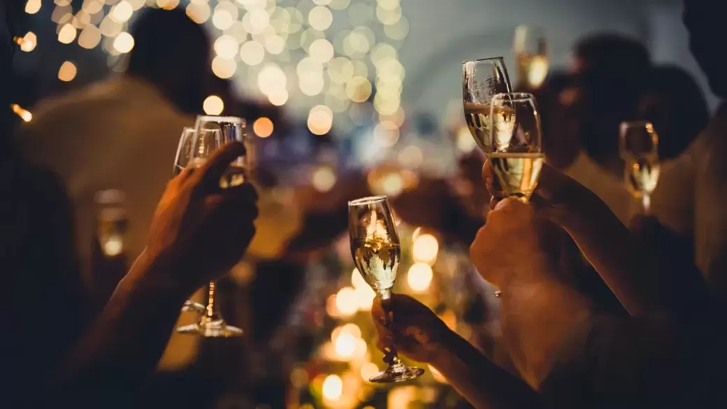 A group of people at a Christmas party holding up glasses of champagne