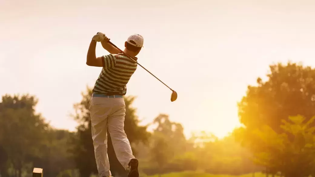 A golfer teeing off on a summer evening