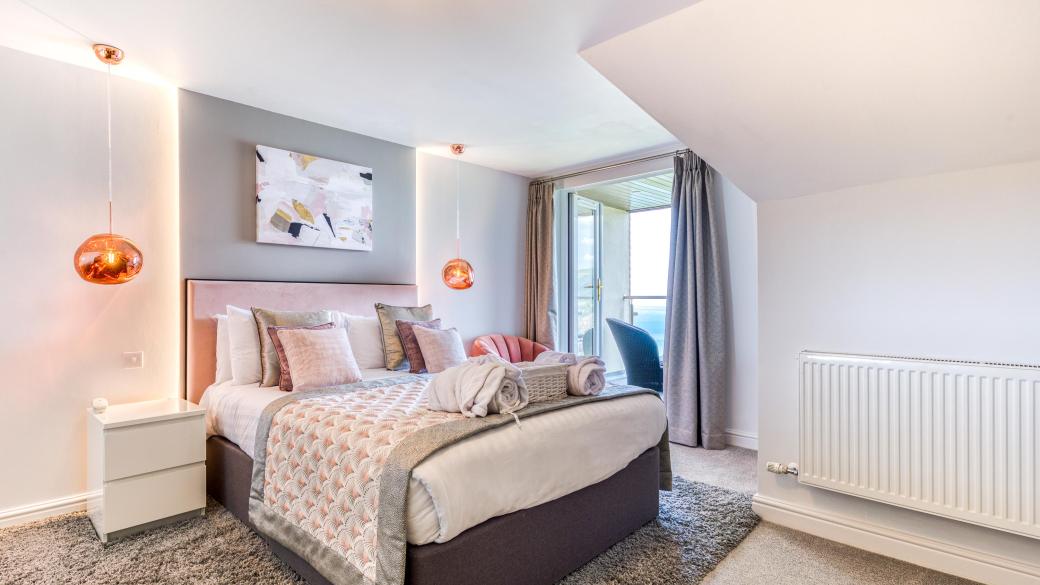 The bed and decor in a deluxe sea view bedroom with a balcony at Sandy Cove Hotel