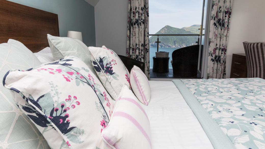 Cushions and pillows on the bed in a Superior Sea View room with a balcony at Sandy Cove Hotel