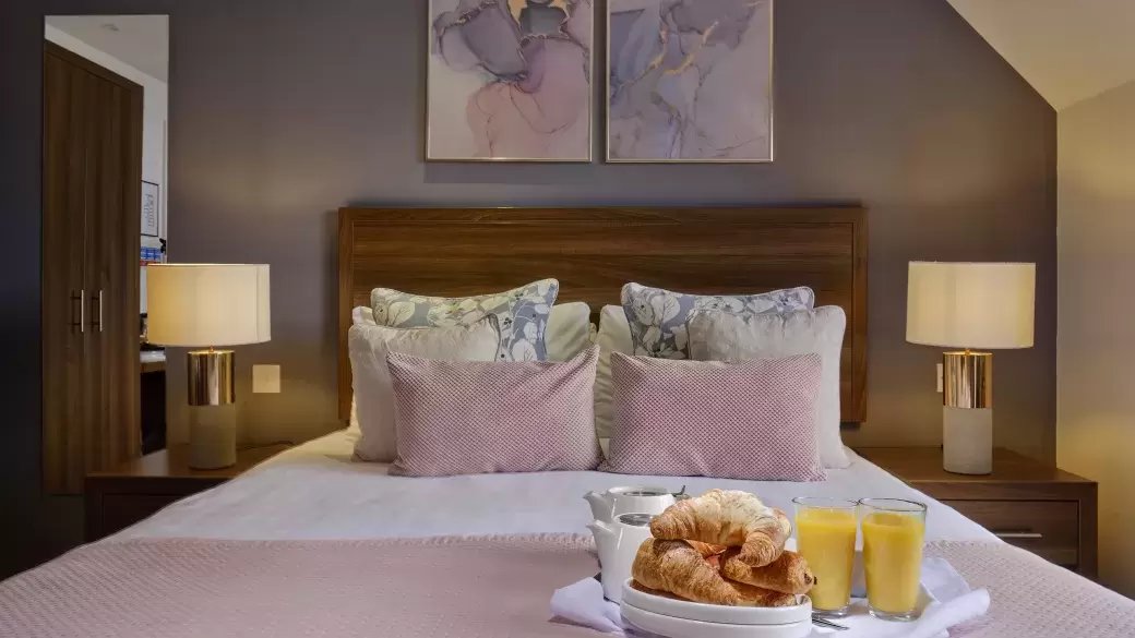 The bed in one of Sandy Cove Hotel's classic sea view with balcony rooms with a breakfast tray on top