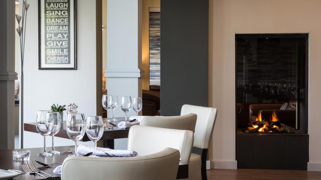 Tables and chairs set for diners inside the Cove Restaurant at Sandy Cove Hotel