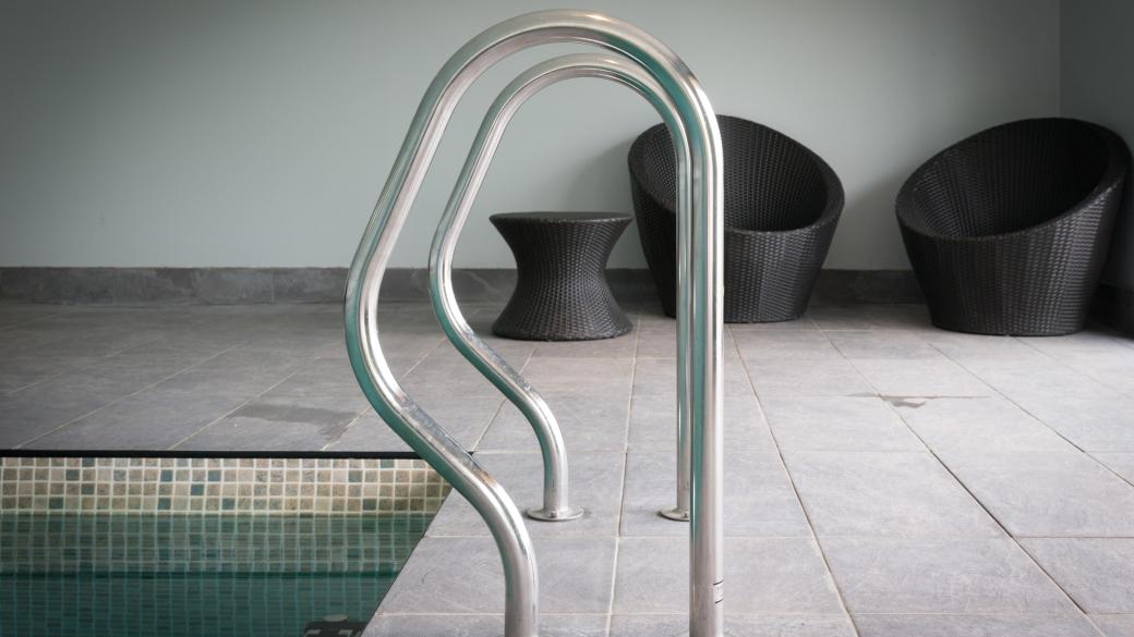 Hand rails by the swimming pool steps with seating in the background at Sandy Cove Hote