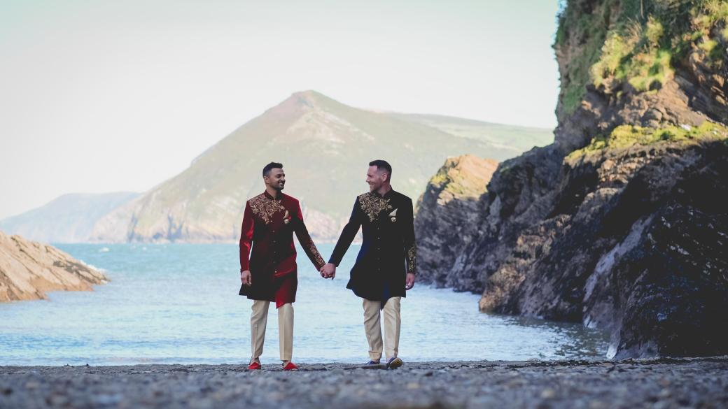 A couple walking on Broadsands beach near Sandy Cove Hotel after their wedding ceremony