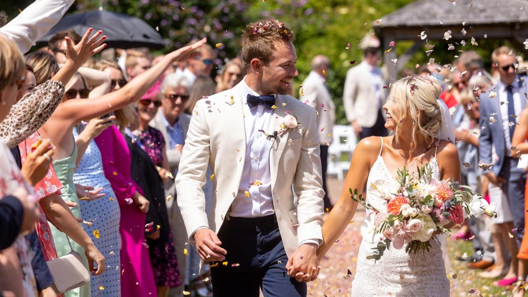 Guests throwing confetti over a bride and groom at Sandy Cove Hotel's the Venue