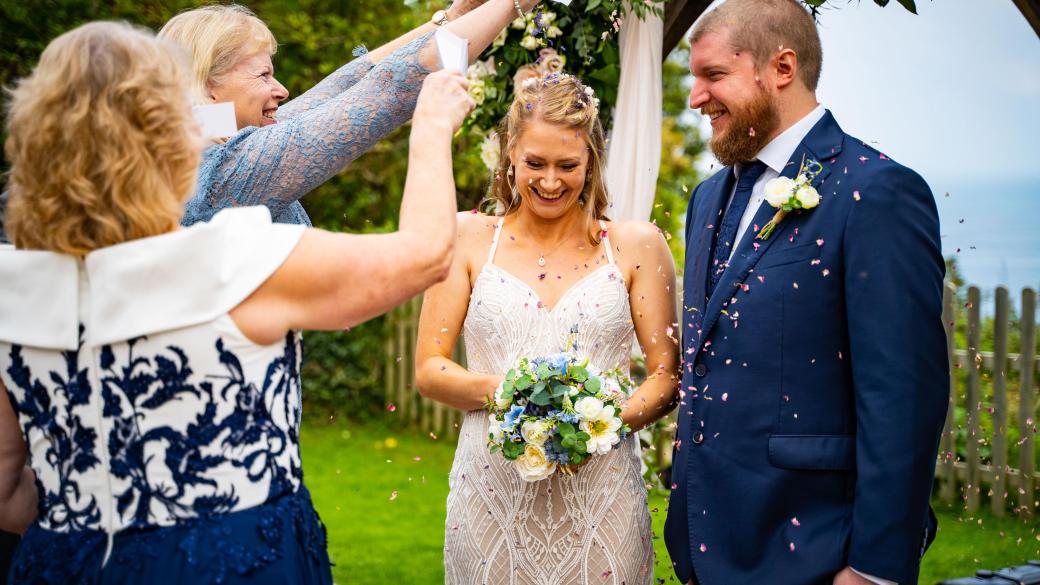 Guests at an intimate wedding throwing confetti over the bride and groom at The Venue, Sandy Cove Hotel