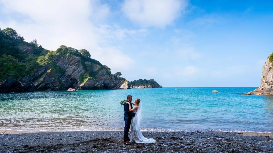 A bride and groom on Broadsands Beach near Sandy Cove Hotel on their wedding day