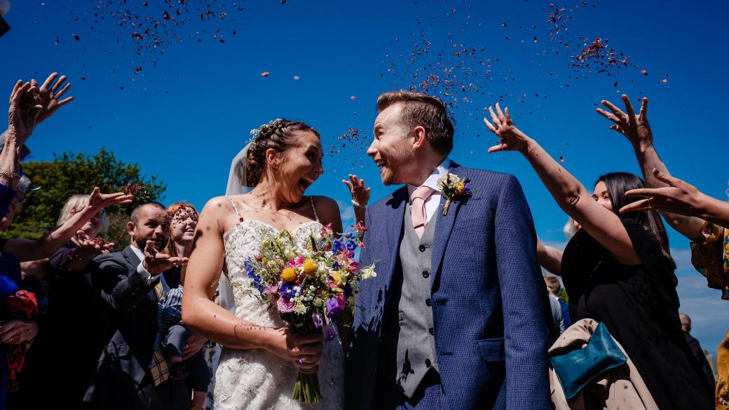 Guests throwing confetti over a bride and groom on their wedding day at Sandy Cove Hotel
