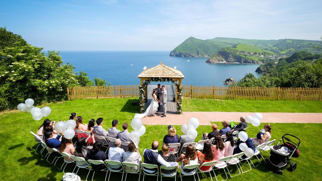 Wedding ceremony outside by the arbour with the view behind at the Sandy cove hotel