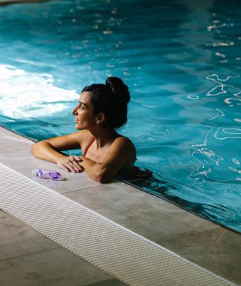 A woman relaxing against the edge of a swimming pool