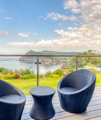 Two chairs and a table on the balcony overlooking the bay in Room 43 at Sandy Cove Hotel