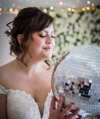 A bride inside the Venue at Sandy Cove looking into a disco ball decoration at her wedding