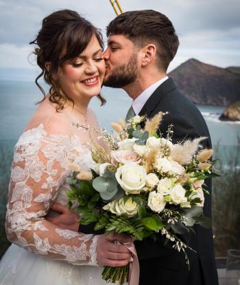 A bride and groom sharing a kiss overlooking the wintery bay at The Venue at Sandy Cove on their wedding day