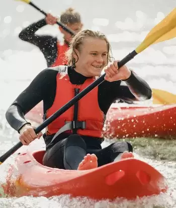 Smiling teenagers kayaking in the sea