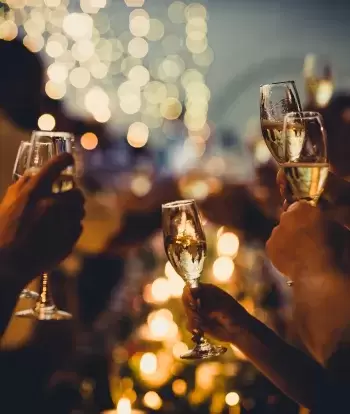 A group of people at a Christmas party holding up glasses of champagne