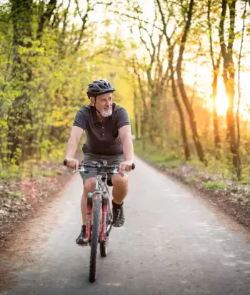 A man riding a bike on a cycle path with trees on either side