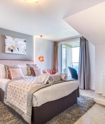 The bed and decor in a deluxe sea view bedroom with a balcony at Sandy Cove Hotel