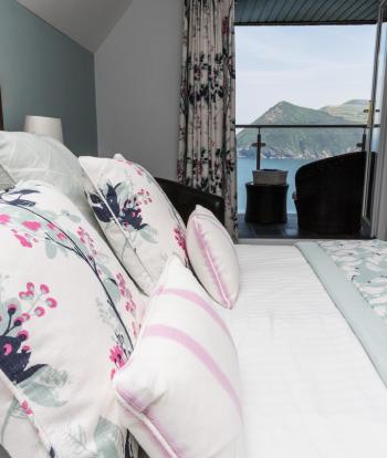 Cushions and pillows on the bed in a Superior Sea View room with a balcony at Sandy Cove Hotel