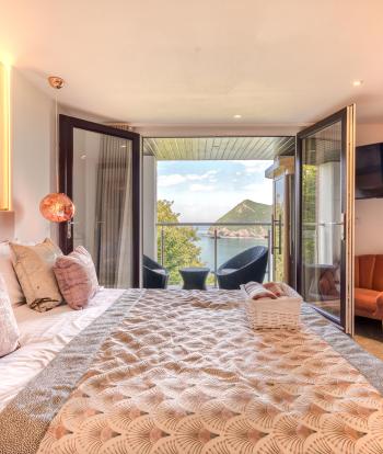 The interior of and executive sea view room with balcony at Sandy Cove Hotel showing the bed and balcony with a view over the bay