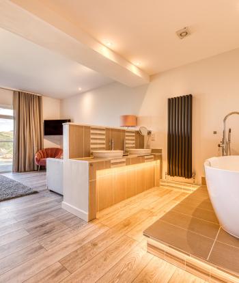 The interior of a luxury sea view room at Sandy Cove Hotel showing the in-room bathtub and balcony