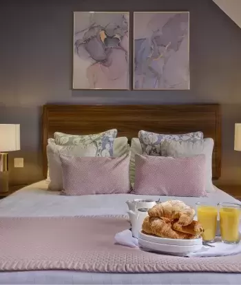 The bed in one of Sandy Cove Hotel's classic sea view with balcony rooms with a breakfast tray on top