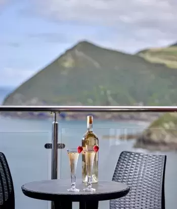 Glasses of wine on a balcony table with a view over the bay in one of Sandy Cove Hotel's bedrooms