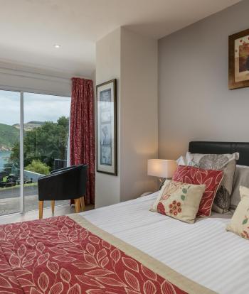 The bed and seating area with a view over the bay in one of the Standard Rooms at Sandy Cove Hotel