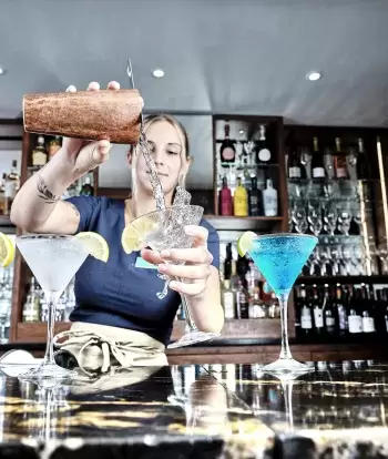 A bartender at Sandy Cove Hotel pouring a cocktail into a glass