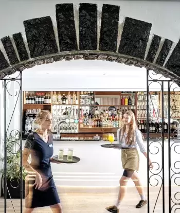 Staff with trays of drinks walking by the bar at Sandy Cove Hotel