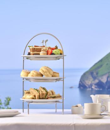 An afternoon tea with sandwiches, scones and cakes served with tea and coffee and with a view of the bay through the window