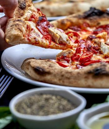 A close up view of a slice of pizza being lifted off a plate at Sandy Cove Hotel