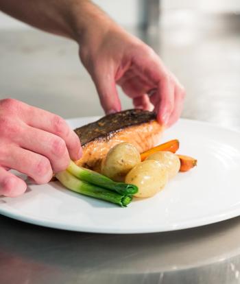 A chef at Sandy Cove Hotel preparing a dish ready to serve