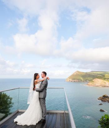 A bride and groom standing on the platform overlooking the bay at The Venue, Sandy Cove Hotel