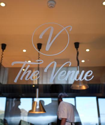 The logo for The Venue at Sandy Cove Hotel on a glass wall
