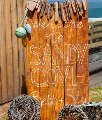 A wedding sign made of drift wood and lobster pots outside The Venue at Sandy Cove Hotel