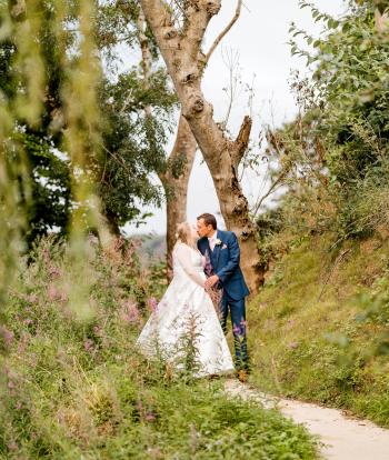 A bride and groom sharing a kiss in the grounds of Sandy Cove Hotel