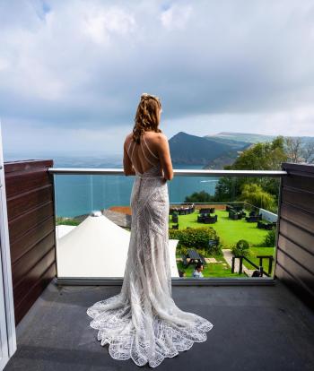 A bride wearing her wedding dress on her bedroom balcony at Sandy Cove Hotel