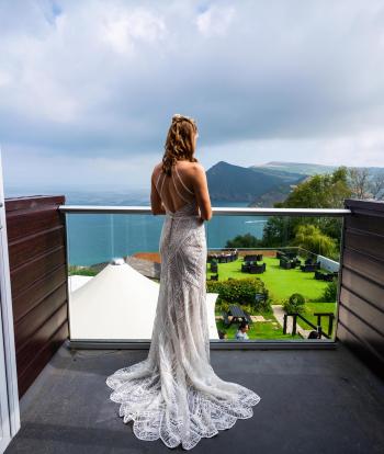 A bride wearing her wedding dress on her bedroom balcony at Sandy Cove Hotel