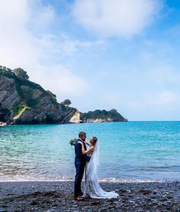 A bride and groom on Broadsands Beach near Sandy Cove Hotel on their wedding day