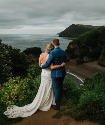 A bride and groom overlooking Broadsands beach and the bay after their wedding at Sandy Cove Hotel