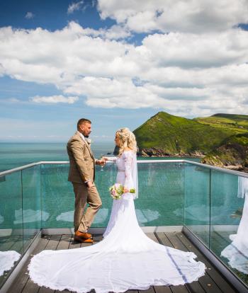 A bride and groom standing on the platform overlooking the bay at The Venue, Sandy Cove Hotel