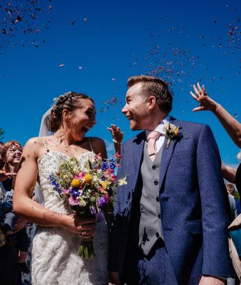 Guests throwing confetti over a bride and groom on their wedding day at Sandy Cove Hotel