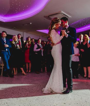 A bride and groom sharing their first dance with family at Sandy Cove's The Venue