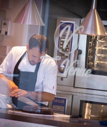 A chef cutting a cake in the kitchen at The Venue, Sandy Cove