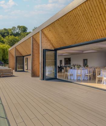 The deck and bi-fold doors of The Venue at Sandy Cove Hotel with tables set up for a wedding reception