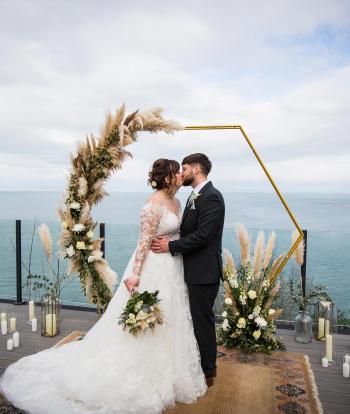 A bride and groom sharing a kiss on the deck of the Venue overlooking the bay